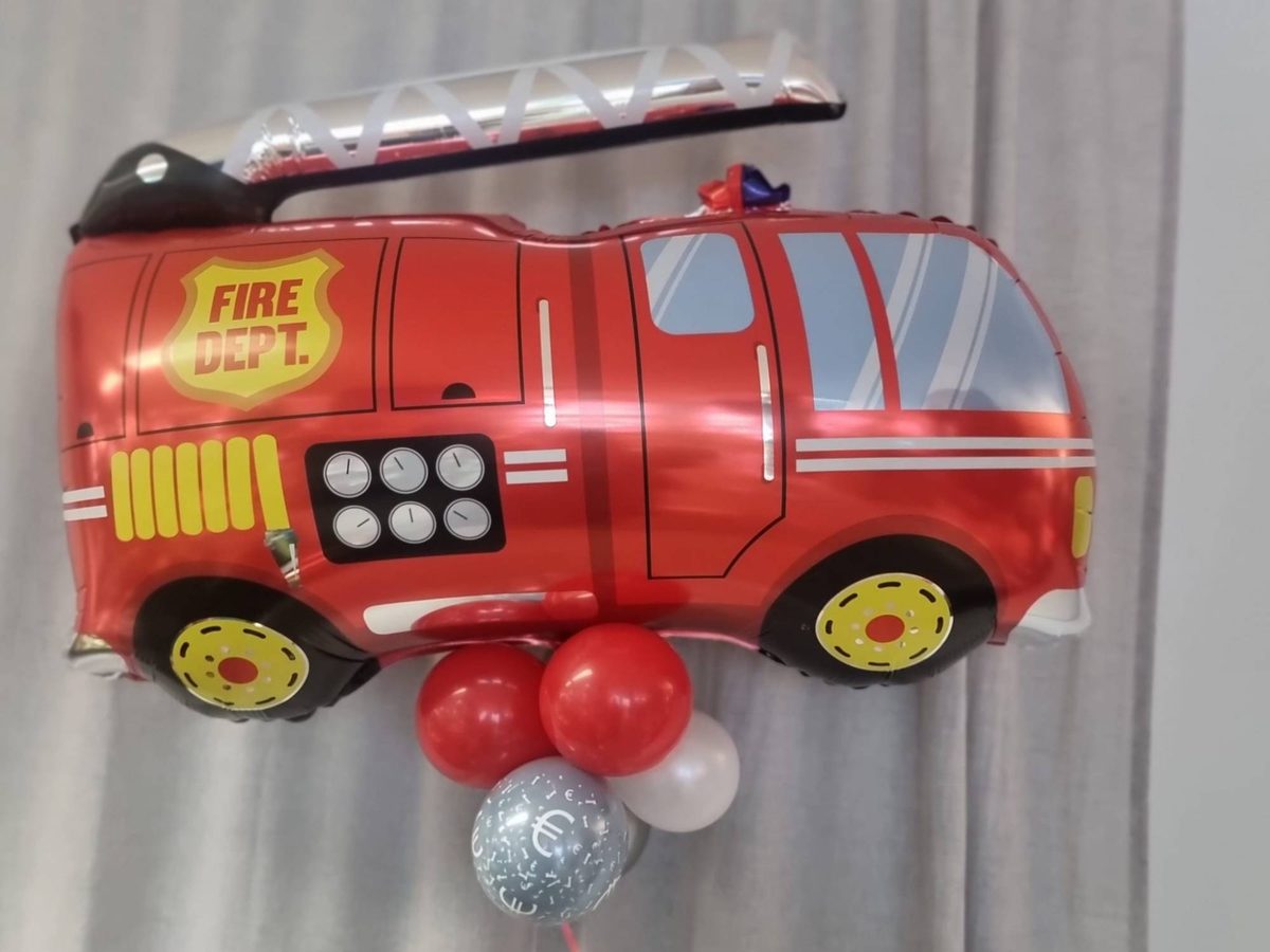 Motivballon Feuerwehrauto aus Folie, schwebend mit Helium, darunter ein Ballonfuß in Rot, Weiß und Silber mit Geldfach