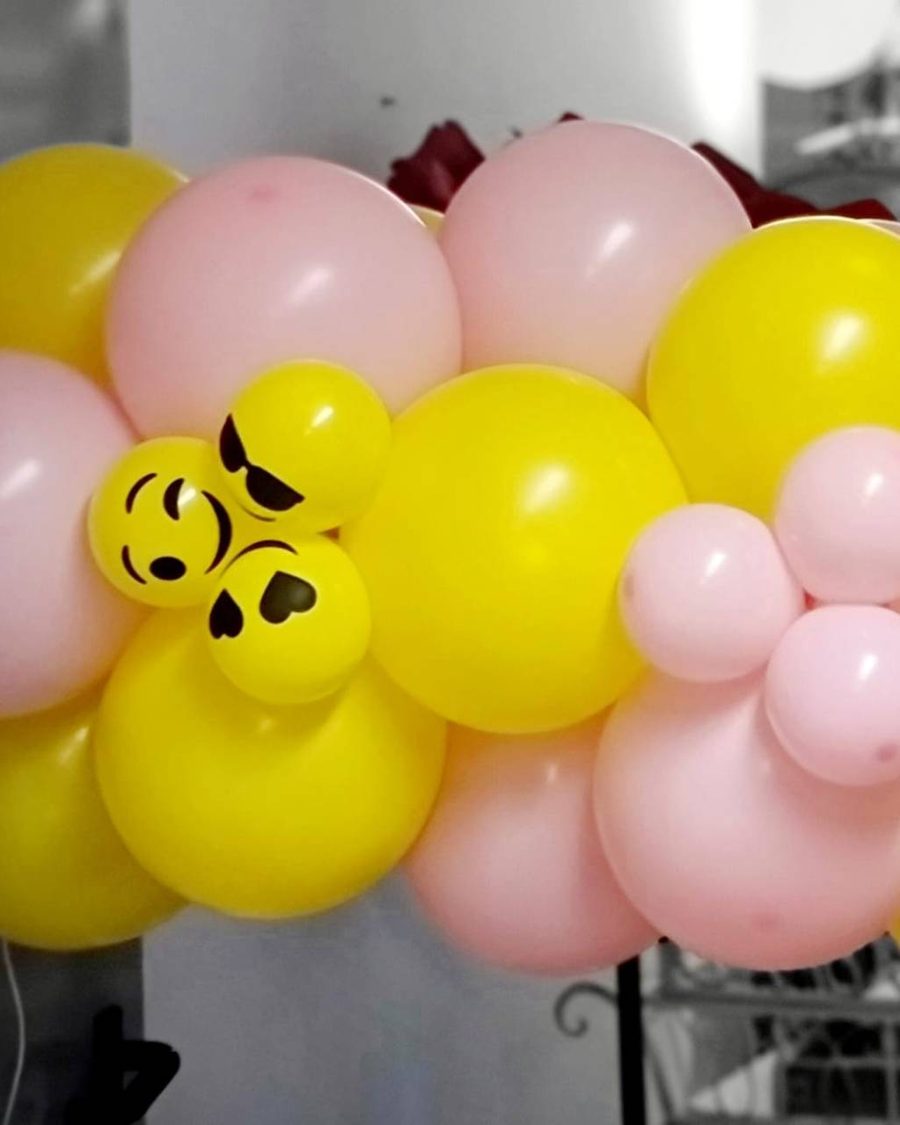 Ballongirlande aus gelben und rosafarbenen Ballons mit aufgedruckten Emoji-Gesichtern