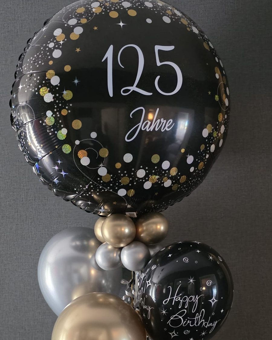 Großer schwarzer Folienballon mit weißem Schriftzug „125 Jahre“ und Konfetti-Print, dazu Ballons in Gold, Silber und Schwarz