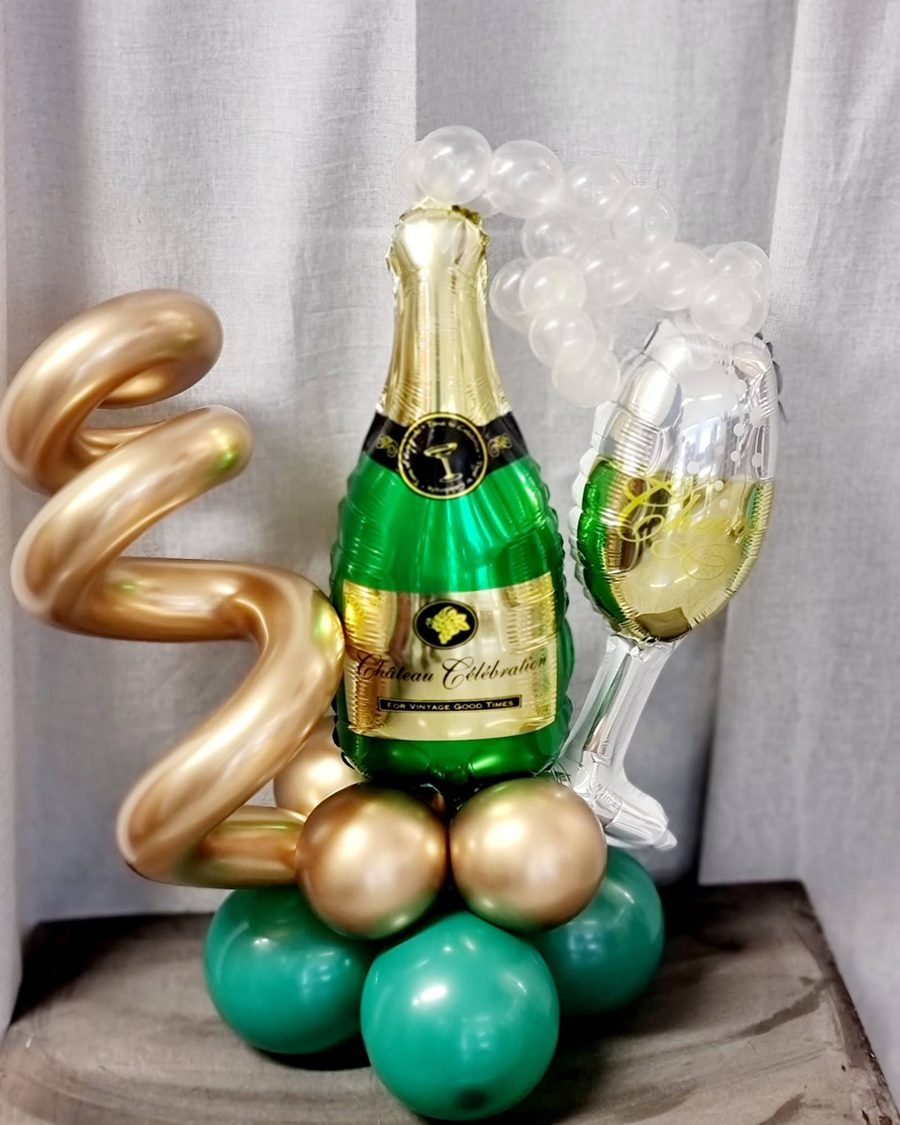 Ballonstand mit Sektflasche und Sektglas aus Folie, aufsteigenden Perlen und einem Fuß aus grünen und goldenen Ballons